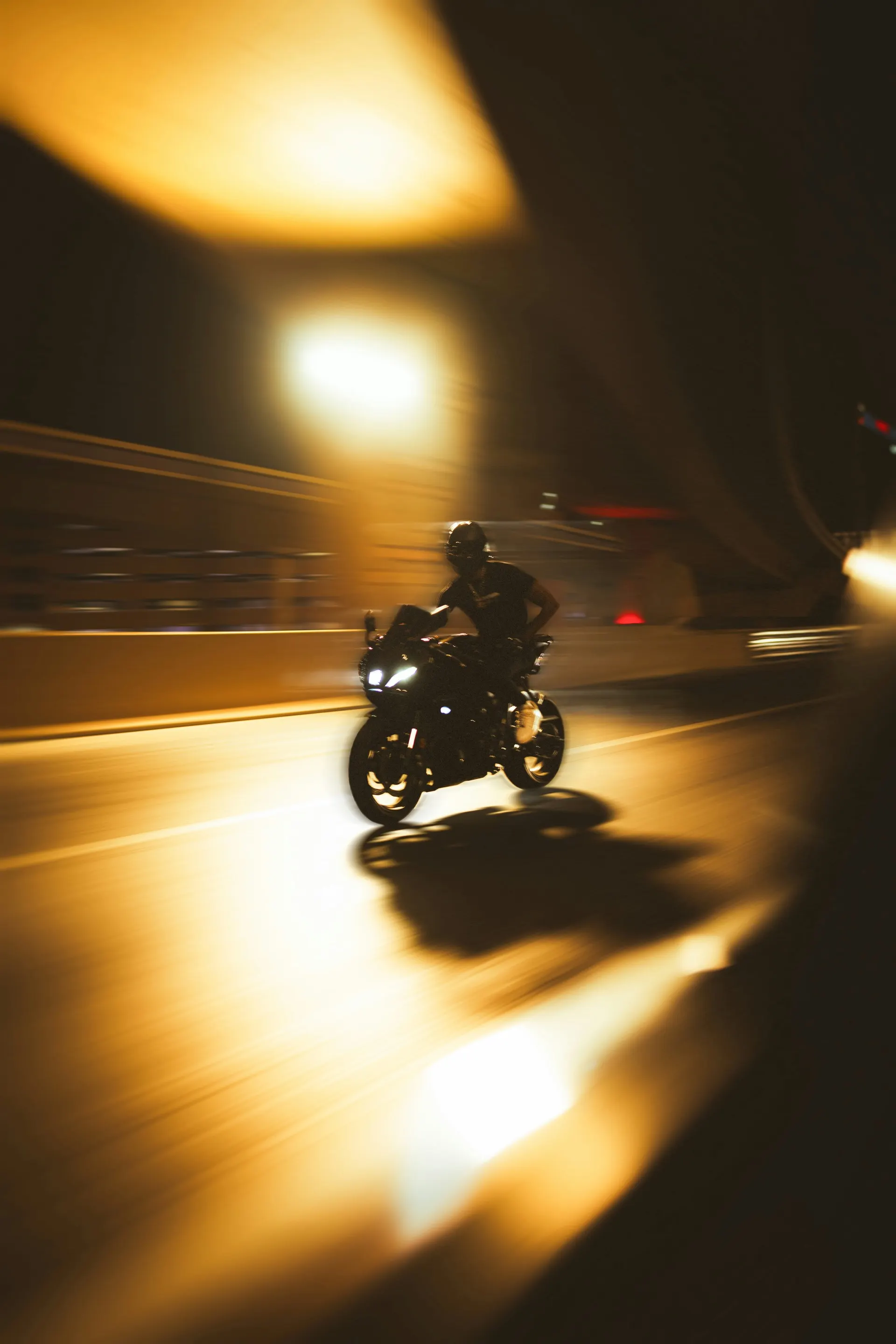 Motion-blurred shot of a rider accelerating through an underpass at night, lights streaking