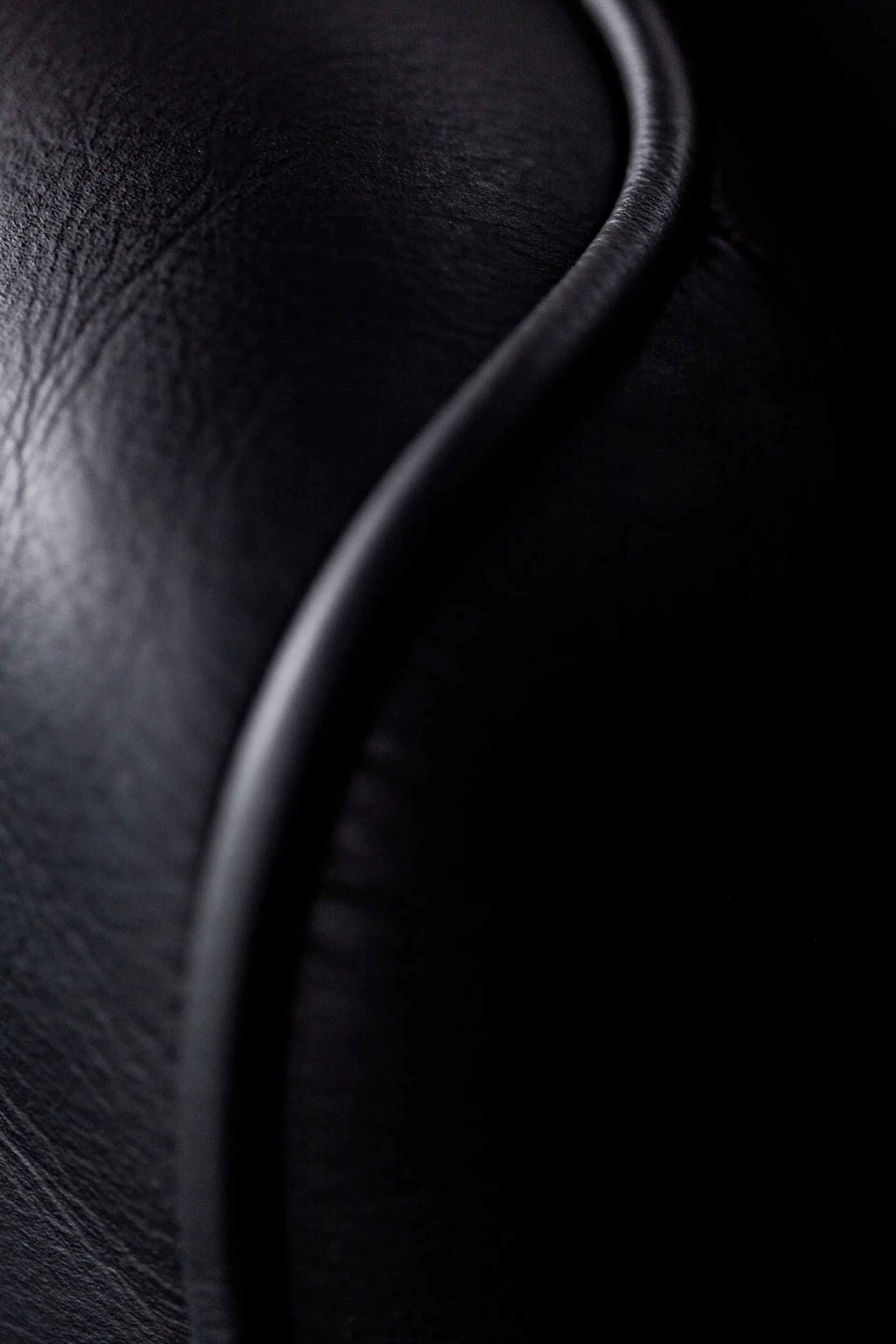 Macro detail of hand-stitched black leather seat seam